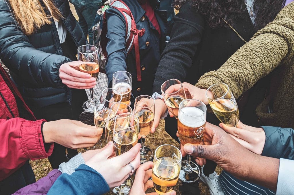 Photo of people's hands holding glasses of wine and clinking glasses in celebration