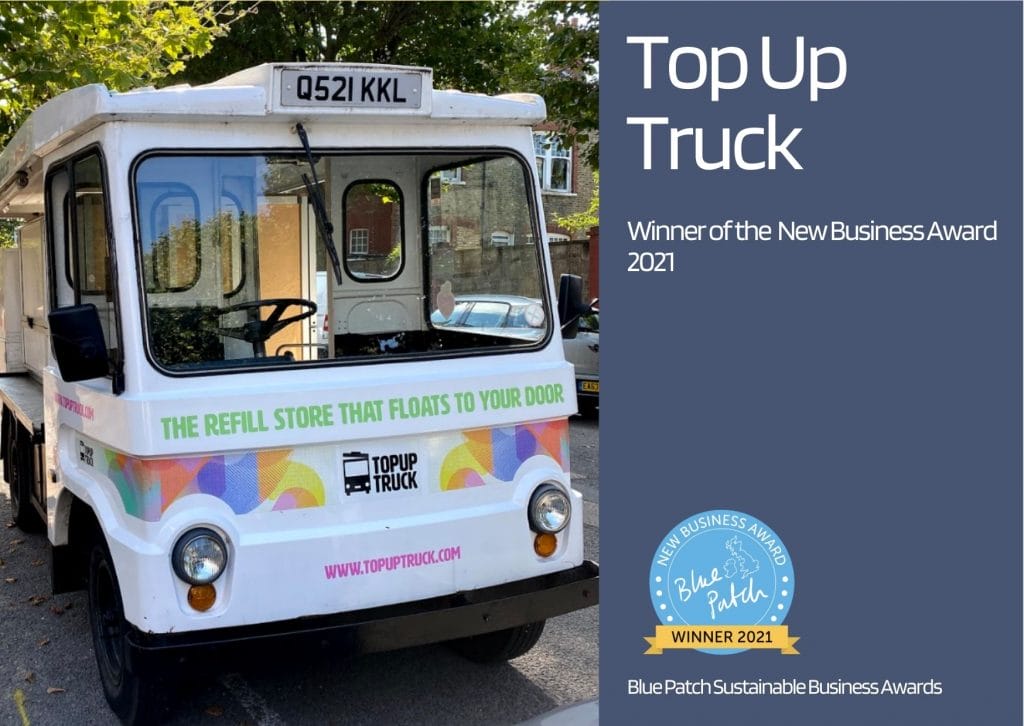 A milk float providing refills, in a sunny street for low carbon food shopping