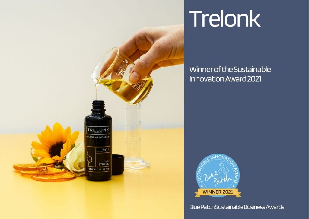 organic golden oil poured from a glass beaker into a black bottle, on a yellow table, with a sunflower, showing winning sustainable brand Trelonk, Cornwall